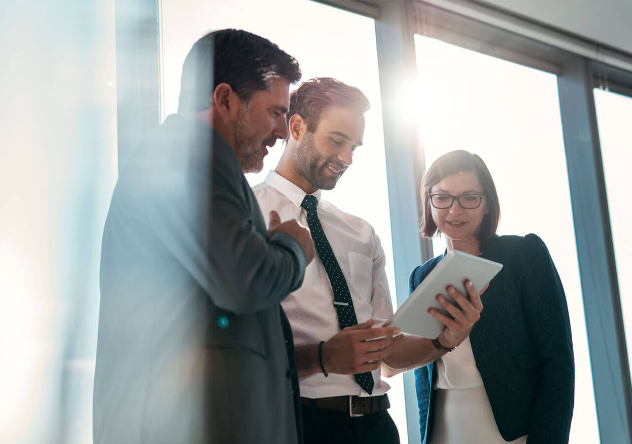 Três pessoas conversando e olhando para um tablet